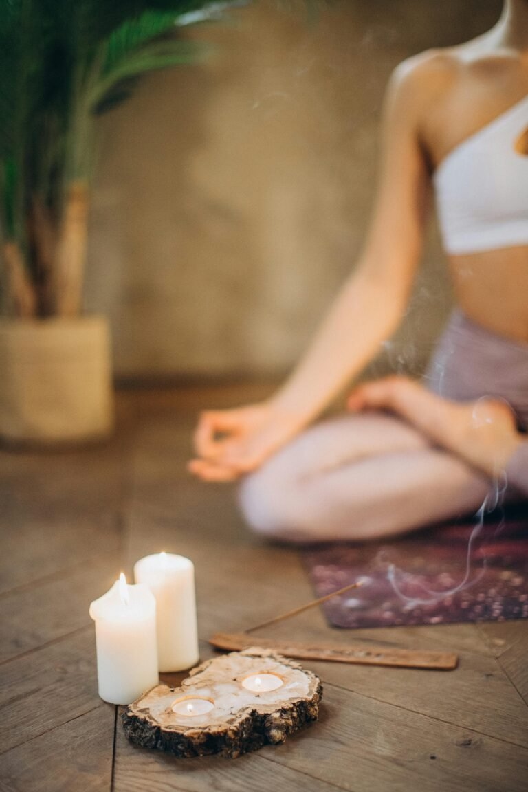 Woman practicing meditation in lotus pose with candles and incense, focusing on wellness and relaxation.